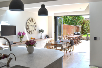 View  from the kitchen showing the light and airy family kitchen/dining room.  Illustrates how the lowered floor,  roof lights and large bi-fold doors transforms the interior which now flows into the garden via a paved terrace.