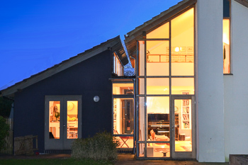 Image of the rear of the house at dusk showing how the large split-level garden extension visually and spatially links via a glazed corner.