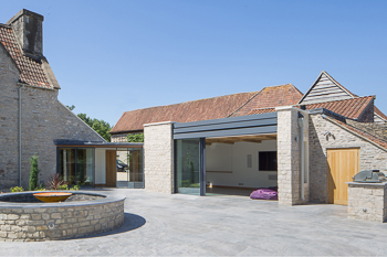 Photograph highlighting the view from the new landscaped terrace leading into the new garden room with has large pocket doors doors to create a much improved relationship between the house and the garden.