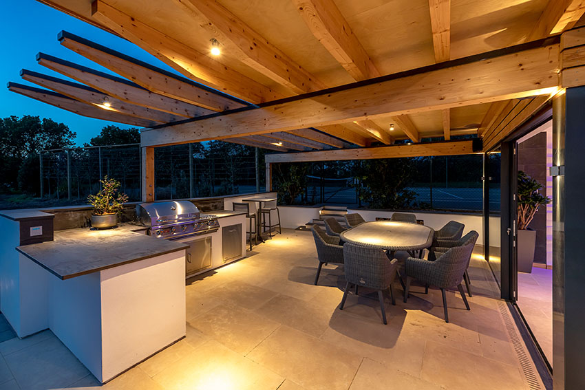 Image of outdoor dining and kitchen/barbecue area with exposed timber structure canopy