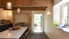 Renovated kitchen with light streaming in through mullioned window and traditional hearth beyond