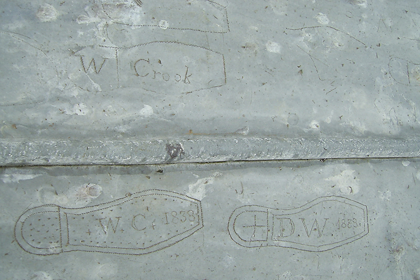 image of lead roof with grafitti from 18th century of shoe outlines  with names within