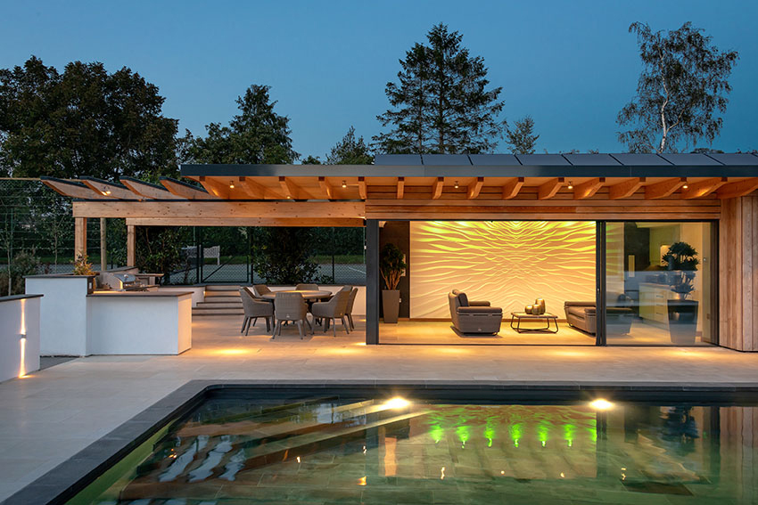 Elevation view of the lit swimming pool, poolside building with coloured lights