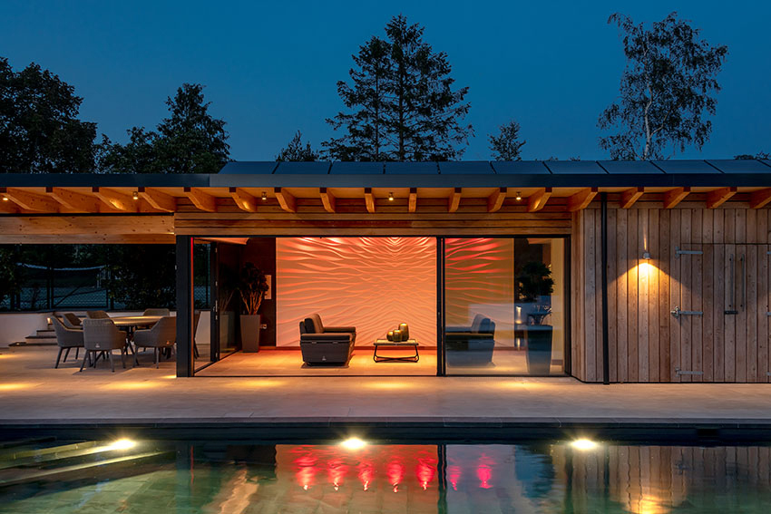 Elevation view of the lit swimming pool, poolside building with coloured lights