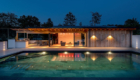 Elevation view of the lit swimming pool, poolside building with coloured lights