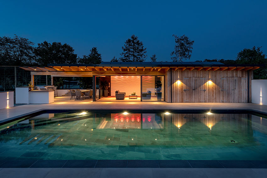 Elevation view of the lit swimming pool, poolside building with coloured lights