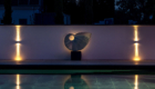 night shot of sculpture at end of poolside terracing with romantic lighting