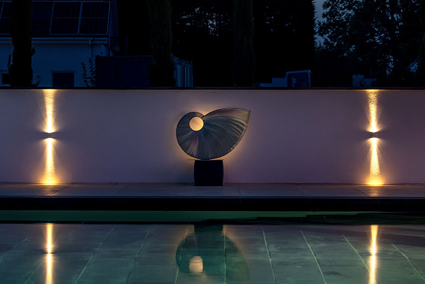 night shot of sculpture at end of poolside terracing with romantic lighting